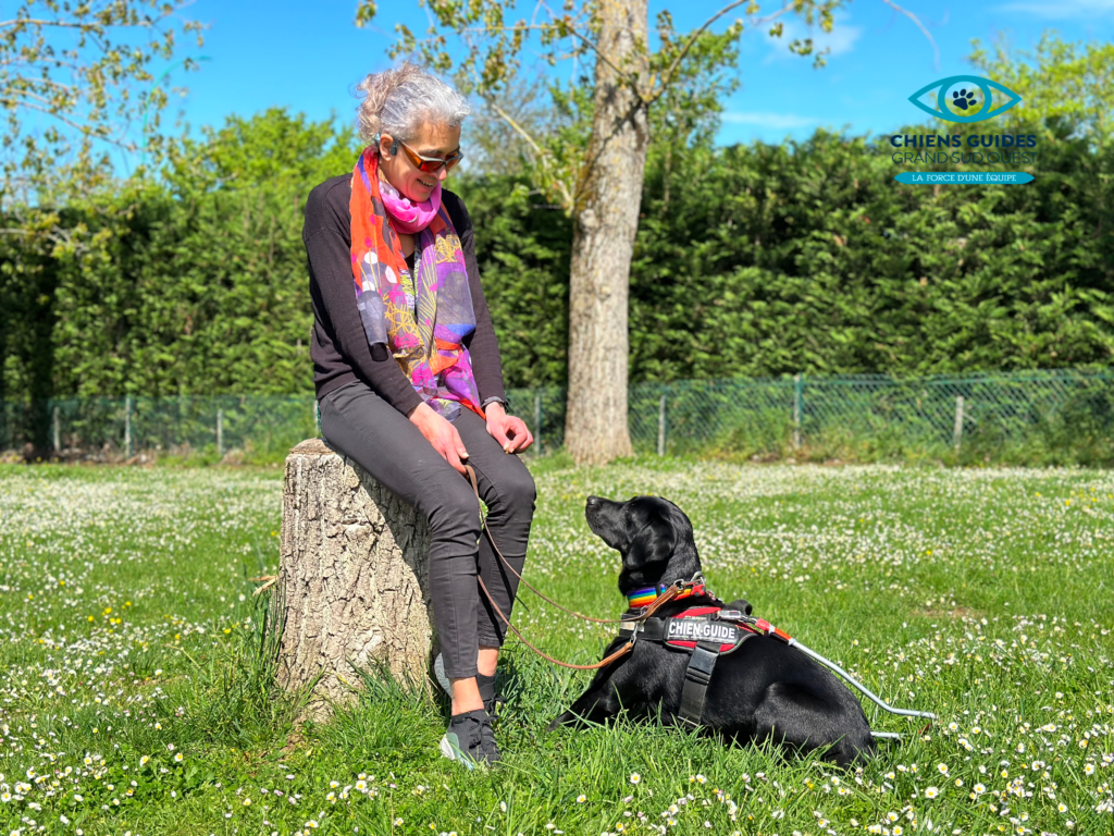 Un maître chien guide avec son chien qui est assis sur la pelouse