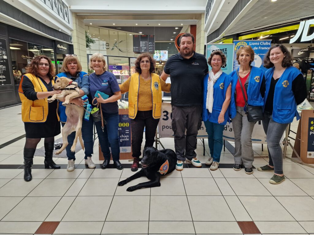 Les Lions Clubs devant le stand de vente accompagné par l'un de nos maîtres déficient visuel et son chien guide
